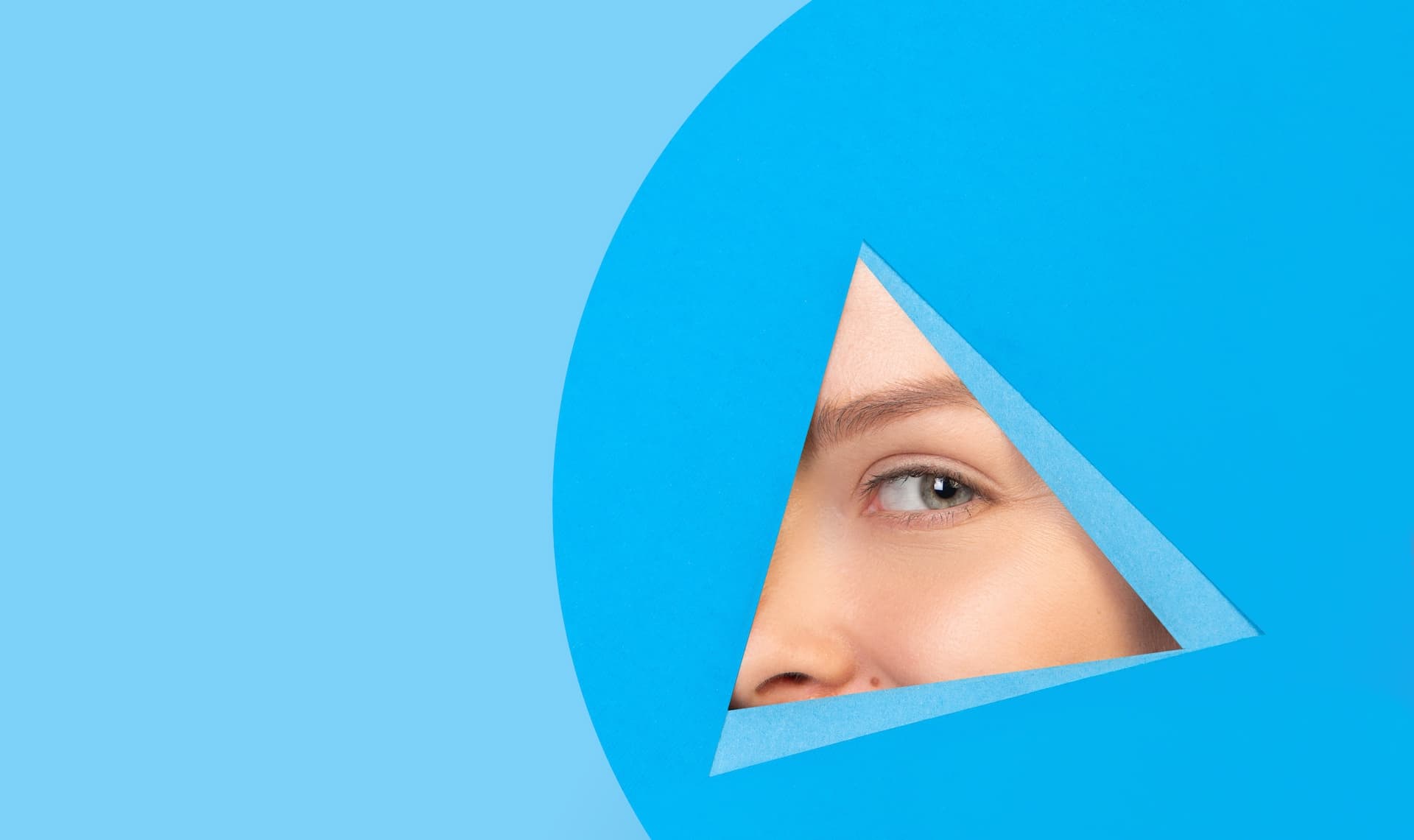 Female eye-looking, peeking through a triangle blue background